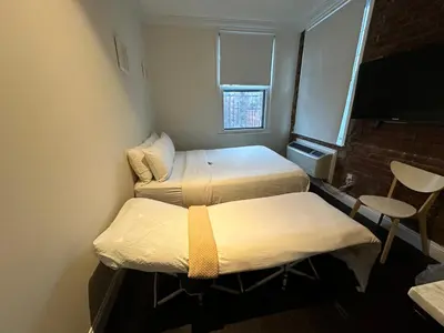 a small room with two beds and a window at East Village Hotel in New York