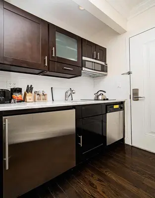a kitchen with black cabinets and stainless steel appliances at East Village Hotel in New York