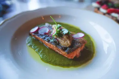 a white plate with a piece of meat and green sauce at Hotel Rock Lititz in Lititz