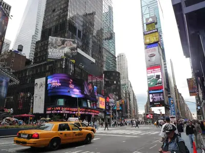 a yellow taxi cab driving down a busy city street at Business & Family Friendly Balcony Jacuzzi Free Park in Jersey City