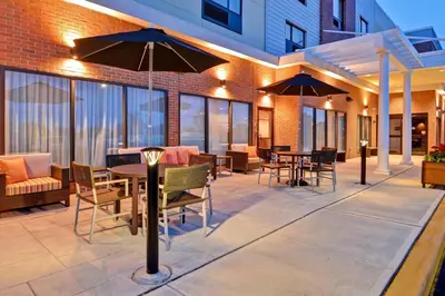 an outdoor patio with tables and chairs and umbrellas at TownePlace Suites by Marriott Bridgewater Branchburg in Branchburg Park