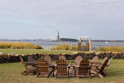 four wooden chairs and a table in front of the water at Collective Retreats Governors Island in New York