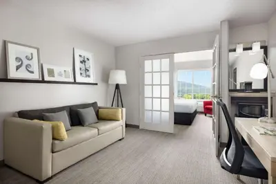 a living room with a couch and a room with a bed at Country Inn & Suites by Radisson, Big Flats (Elmira), NY in Horseheads