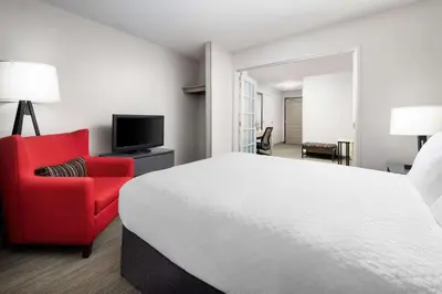 a hotel room with a bed and a red chair at Country Inn & Suites by Radisson, Big Flats (Elmira), NY in Horseheads