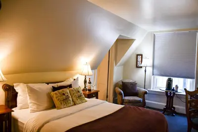 a bedroom with a bed and a chair and a window at The Sayre Mansion in Bethlehem