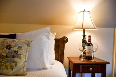 a bed with a lamp and two wine glasses on a table at The Sayre Mansion in Bethlehem