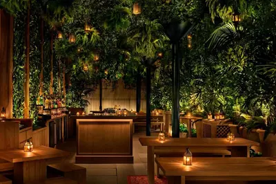 a restaurant with tables and plants on the wall at The Times Square EDITION New York in New York