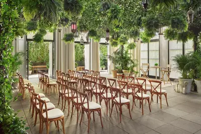 a row of chairs and tables in a room with plants at The Times Square EDITION New York in New York