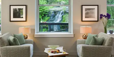 a living room with two chairs and a waterfall seen through a window at Ledges Hotel in Hawley