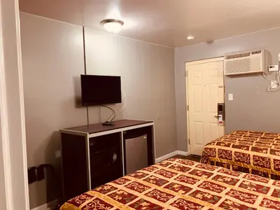 a hotel room with two beds and a flat screen tv at Red Carpet Inn - Norristown in Norristown