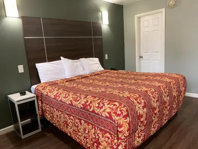 a bedroom with a bed with a orange bedspread at Red Carpet Inn - Norristown in Norristown
