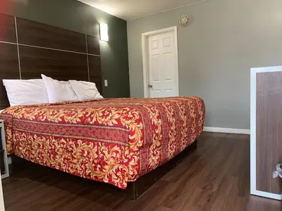 a bedroom with a bed with a red blanket on it at Red Carpet Inn - Norristown in Norristown