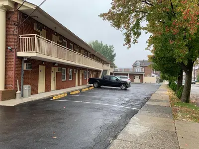 a black car parked in a parking lot next to a building at Red Carpet Inn - Norristown in Norristown
