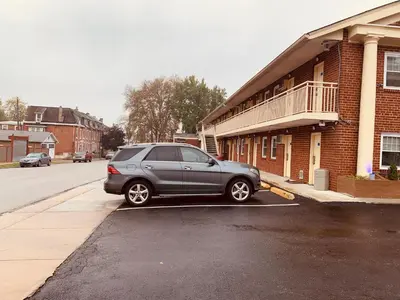 a gray car parked in a parking lot next to a building at Red Carpet Inn - Norristown in Norristown