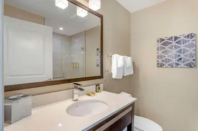 a bathroom with a sink and a toilet and a mirror at Best Western Plus Philadelphia-Pennsauken Hotel in Cherry Hill