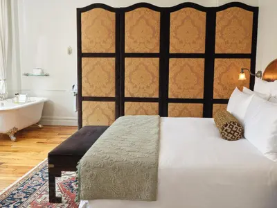 a bedroom with a bed and a tub and a sink at The Ned NoMad in New York