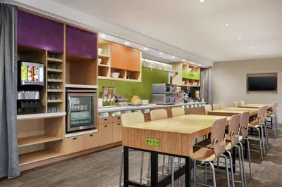 a restaurant with tables and chairs and a kitchen at Home2 Suites By Hilton Warminster Horsham in Warminster