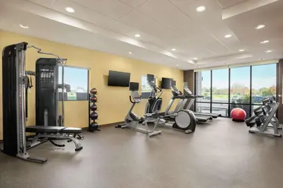 a gym with treadmills and exercise equipment and windows at Home2 Suites By Hilton Warminster Horsham in Warminster