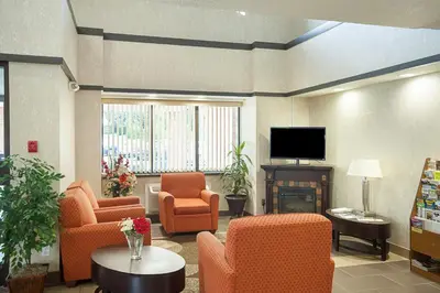 a living room with chairs and a tv and a table at Motel 6-Binghamton, NY in Binghamton