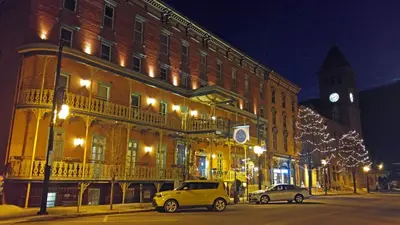 two cars parked in front of a building with a clock tower at The Inn at Jim Thorpe in Jim Thorpe
