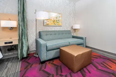 a living room with a blue chair and a stool at Home2 Suites By Hilton Newark Airport in Newark