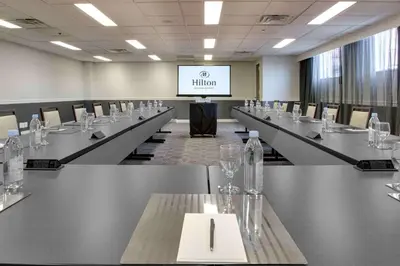 a conference room with long tables and a screen at Hilton Newark Airport in Elizabeth