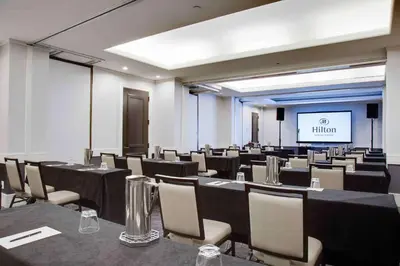 a conference room with tables and chairs and a screen at Hilton Newark Airport in Elizabeth