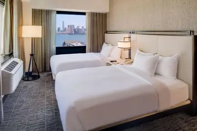 two beds in a hotel room with a window at DoubleTree by Hilton Hotel & Suites Jersey City in Jersey City