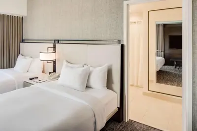 a hotel room with two beds and a mirror at DoubleTree by Hilton Hotel & Suites Jersey City in Jersey City