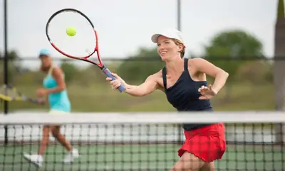 a woman hitting a tennis ball with a racket at Hilton Short Hills in Short Hills