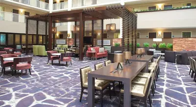 a lobby of a hotel with tables and chairs at Embassy Suites by Hilton Philadelphia Airport in Philadelphia