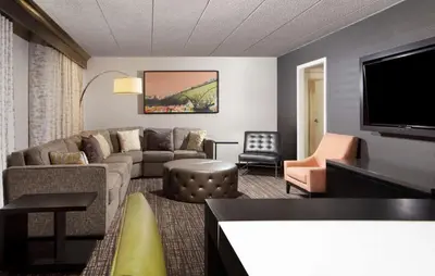 a living room with a couch and a flat screen tv at Embassy Suites by Hilton Philadelphia Airport in Philadelphia