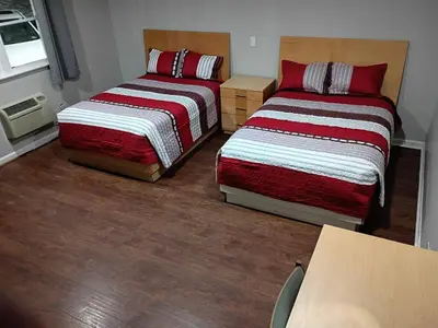 two beds in a small room with wood floors at Bel Air Motor Lodge in Maple Shade