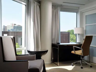 a room with a desk and chairs and windows at The Inn at Penn, A Hilton Hotel in Philadelphia