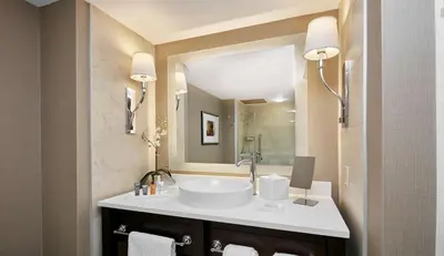 a bathroom with a sink and a large mirror at The Inn at Penn, A Hilton Hotel in Philadelphia