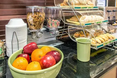 a counter with a bowl of apples and oranges and pastries at Quality Inn Hackettstown - Long Valley in Hackettstown