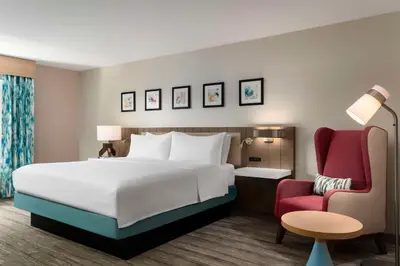 a bedroom with a bed and a red chair at Hilton Garden Inn Kennett Square in Kennett Square