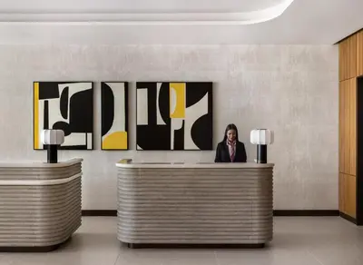 a woman sitting at a reception desk in a lobby at Kimpton Theta New York - Times Square by IHG in New York