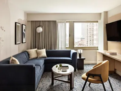 a living room with a blue couch and a table at Kimpton Theta New York - Times Square by IHG in New York