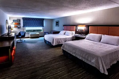 a hotel room with two beds and a desk at Hampton Inn & Suites Staten Island in Staten Island
