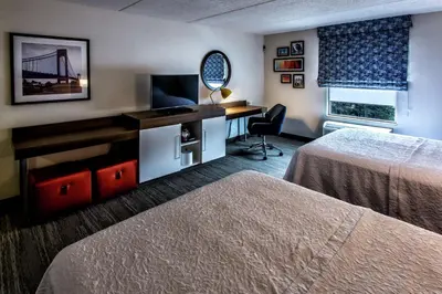 a hotel room with two beds and a desk and a mirror at Hampton Inn & Suites Staten Island in Staten Island