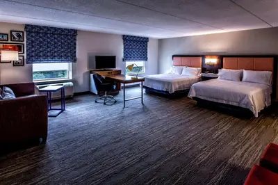 a hotel room with two beds and a desk at Hampton Inn & Suites Staten Island in Staten Island