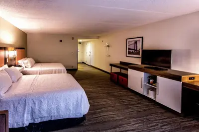 a hotel room with two beds and a flat screen tv at Hampton Inn & Suites Staten Island in Staten Island