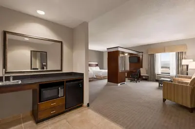 a hotel room with a living room with a bed and a mirror at Hampton Inn & Suites - Mansfield in Mansfield
