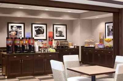 a restaurant with a counter with a table and white chairs at Hampton Inn & Suites - Mansfield in Mansfield