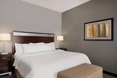 a hotel room with a large bed and a stool at Hampton Inn & Suites - Mansfield in Mansfield