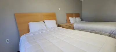 a small bedroom with two beds with white sheets at Superlodge in New Castle