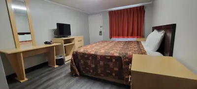 a hotel room with a bed and a desk and a television at Superlodge in New Castle