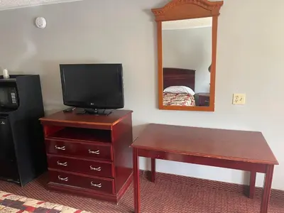 a room with a television on a dresser with a desk and a table sidx at Superlodge in New Castle