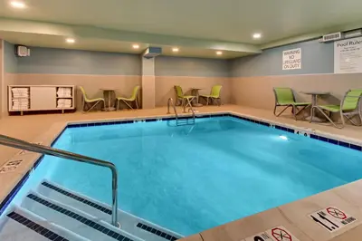 a pool in a hotel room with chairs and tables at Holiday Inn Express Pittston - Scranton Airport by IHG in Pittston